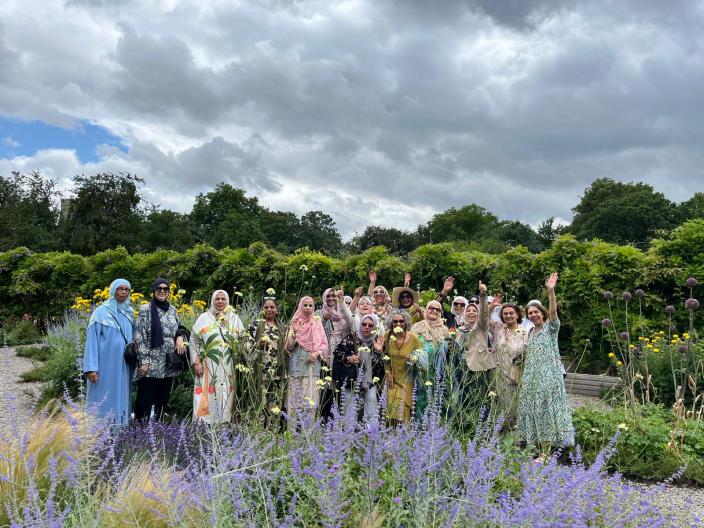 A group of women smiling and waving in a garden