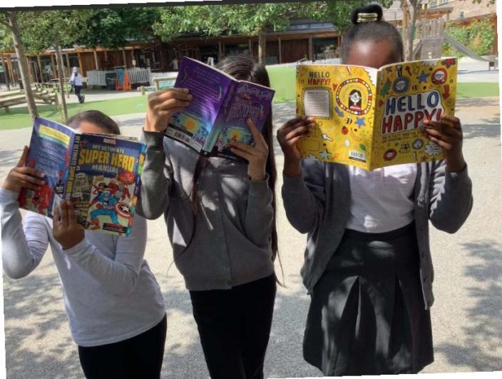 Three children reading books, holding them up in front of their faces